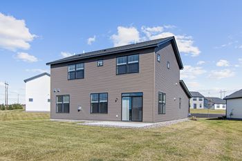 A modern house with a grey facade and a black roof.